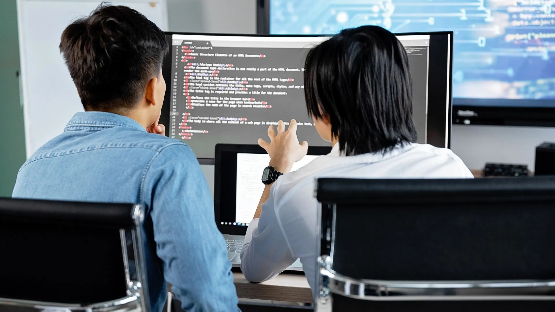 Deux jeunes travaillent ensemble devant un écran de code