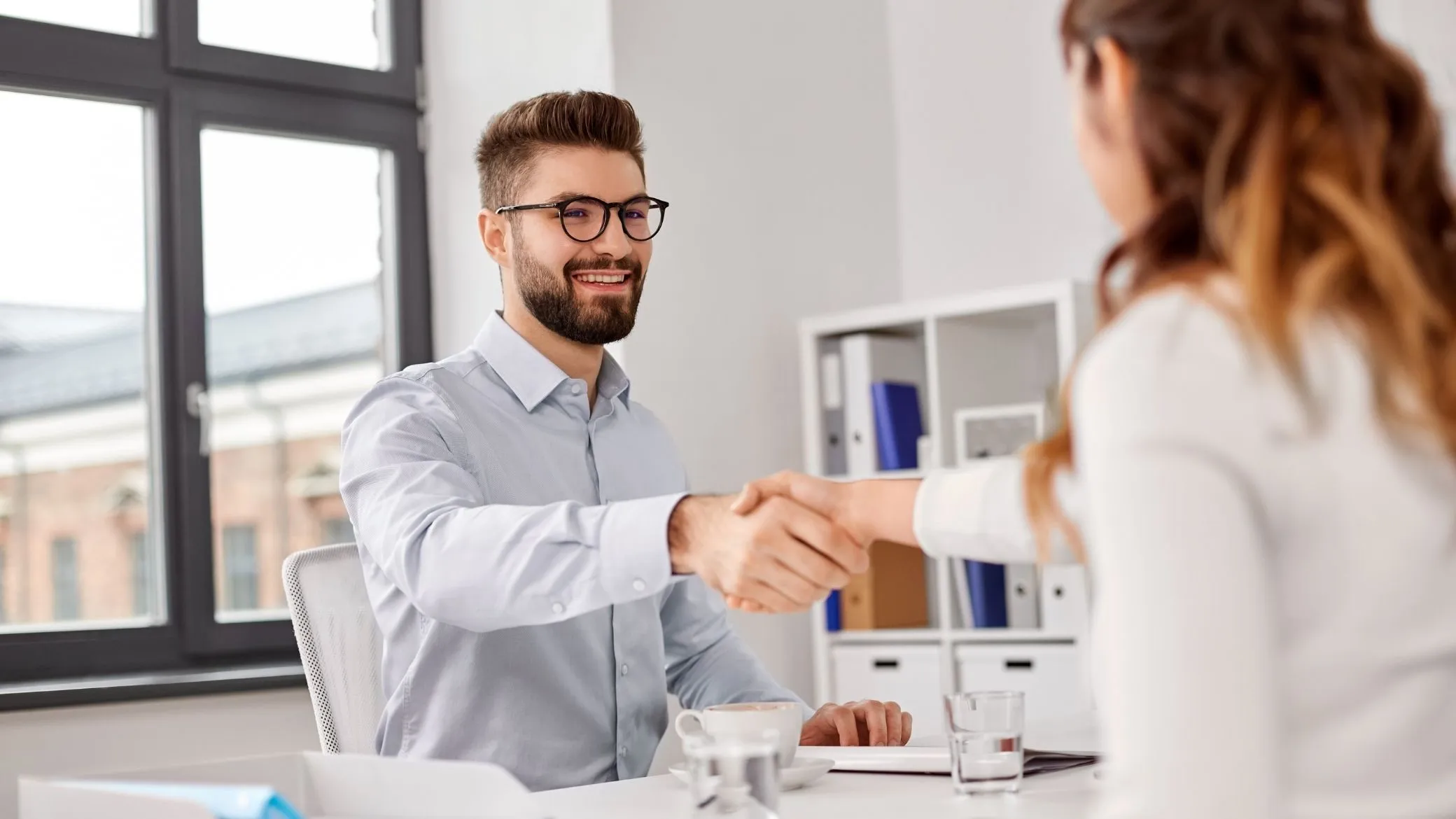 A handshake between a candidate and a recruiter in a bright office