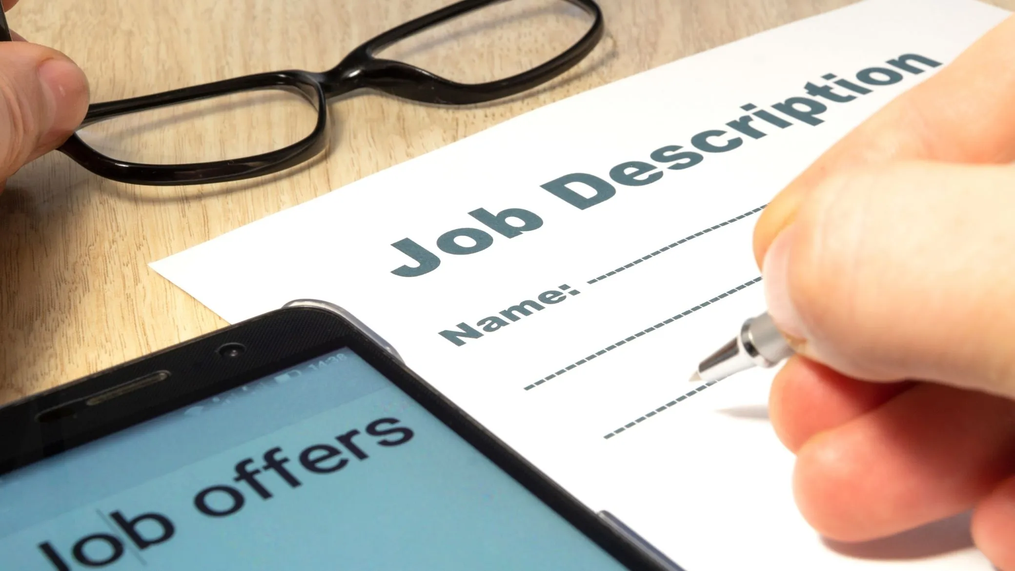 A printed job description and job offers on a phone