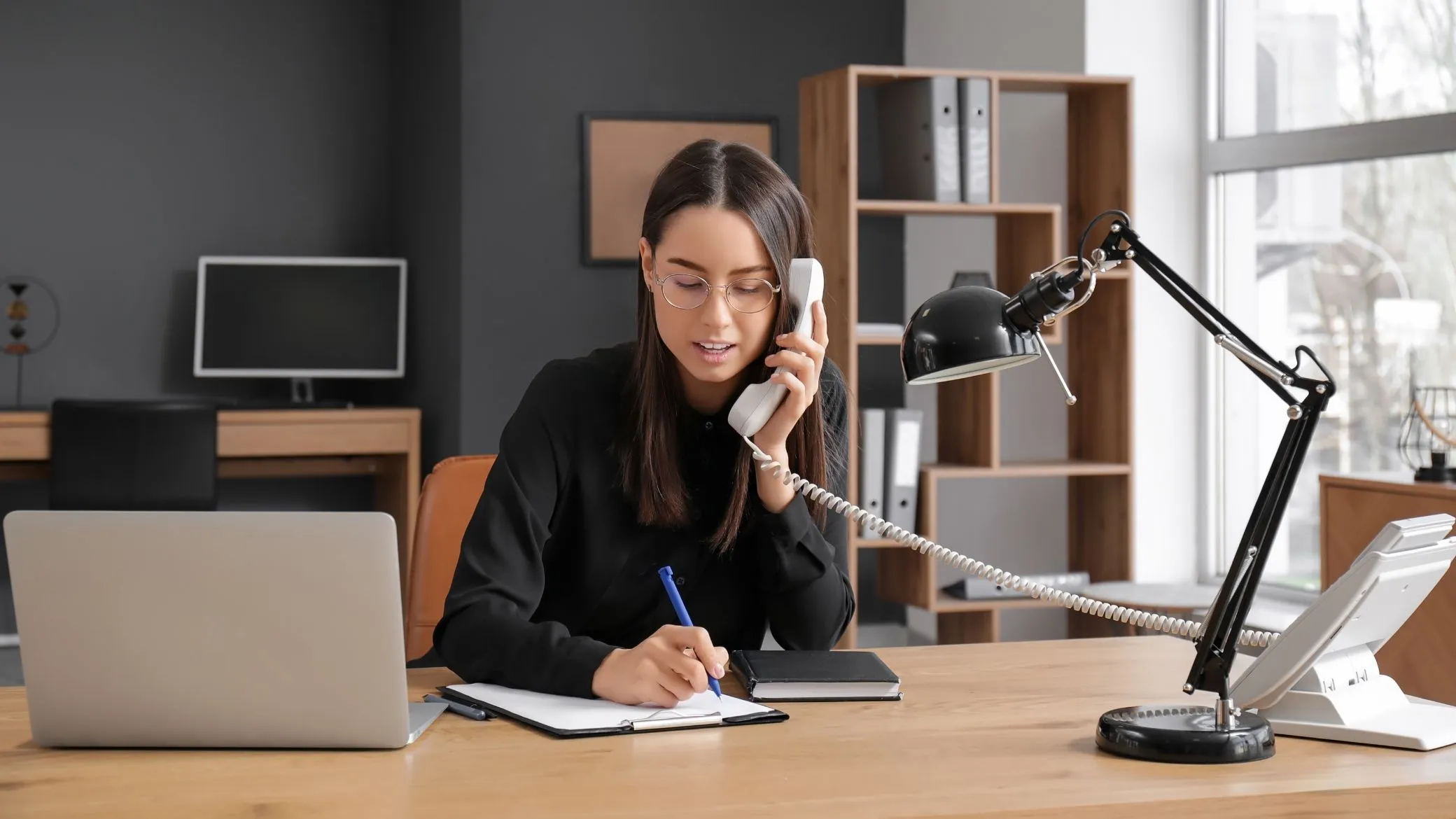 A candidate taking notes during a call on a desk phone