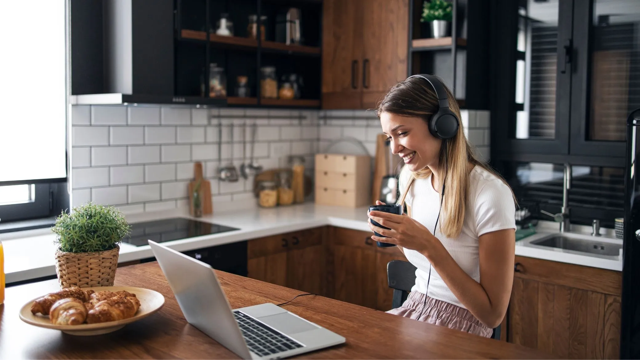 A candidate wearing headphones on a video call from her kitchen